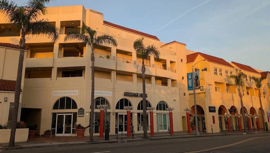 Massage One Wellness (Venice) in Venice, CA, US. Elegant facade with palm trees in warm sunset light.