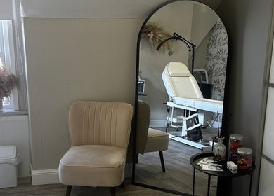 Cozy beauty room at Enhanced by Hannah, Workington, England with mirror, chair, and treatment bed.