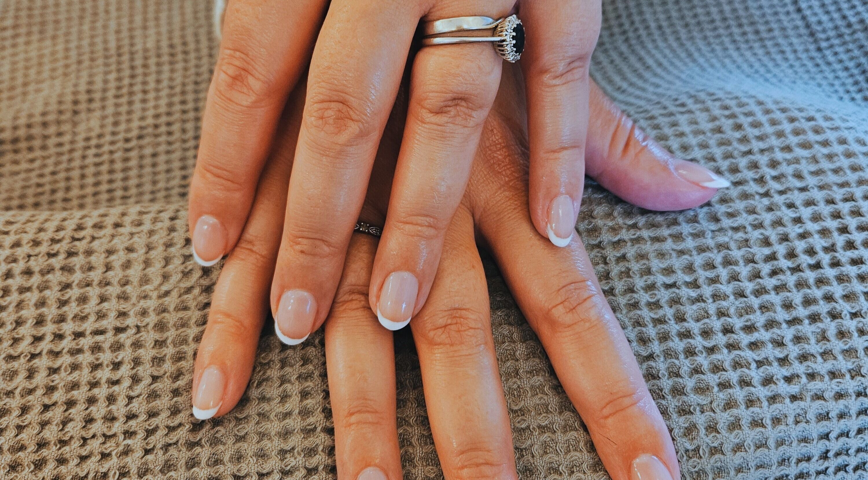Elegant French manicure by EmRose Mobile Beauty Co, East Chinnock, England, GB on a textured surface.
