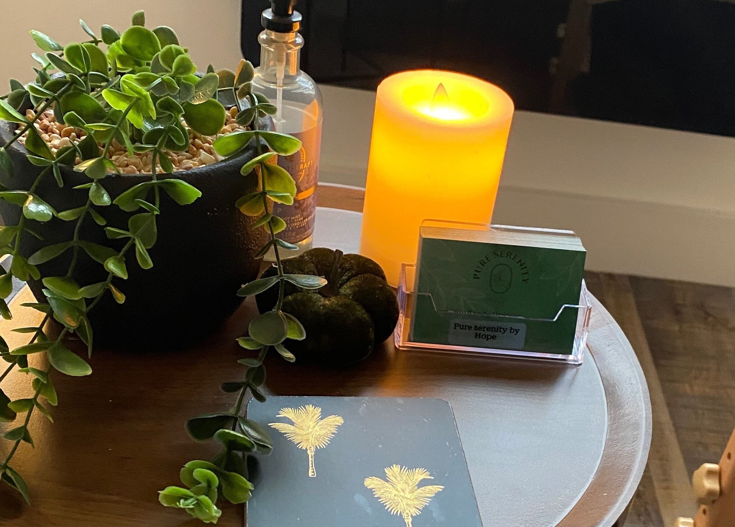 Relaxing corner at Pure Serenity By Hope, Norwich, England, with candle, plant, and decor on wooden table.