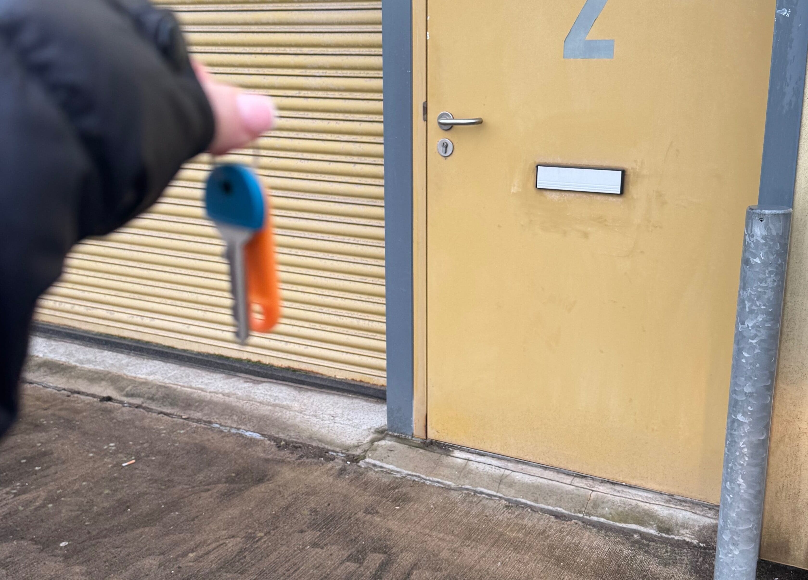 Hand holds key near door at Tails Dog Grooming, Clydebank, Scotland, GB.