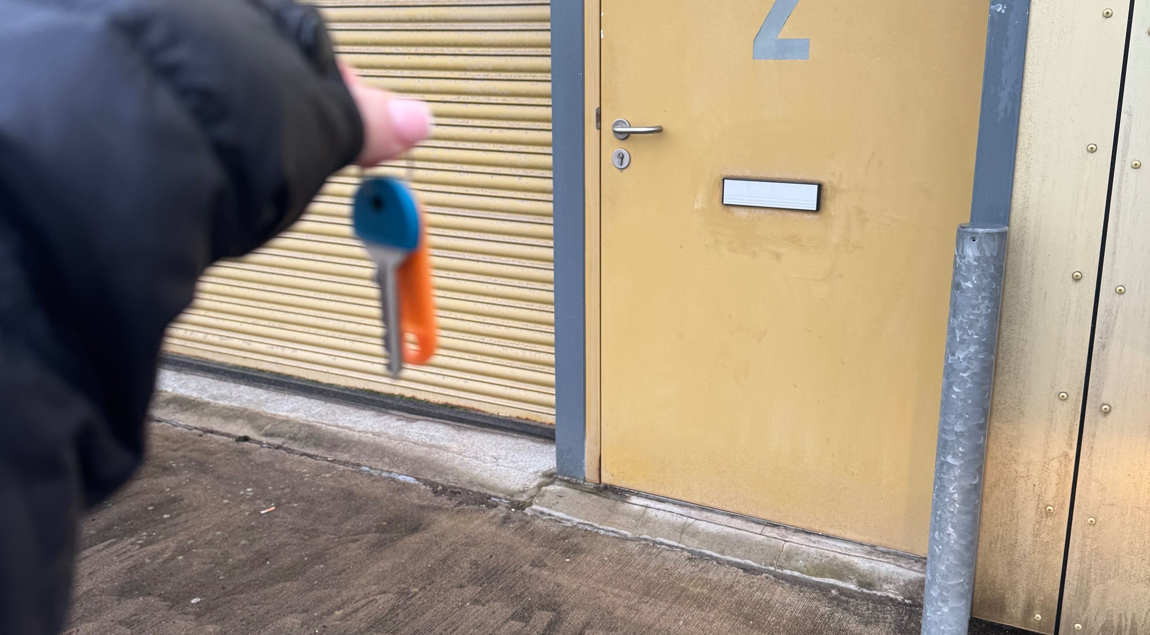 Hand holds key near door at Tails Dog Grooming, Clydebank, Scotland, GB.