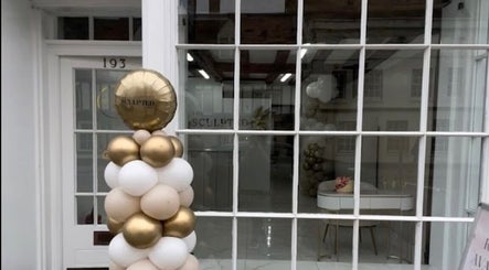 Front view of Beau’s Head Spa in Towcester, England with gold and white balloon decor outside.