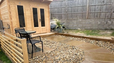 Outdoor seating and wooden cabin at KB Hair, Winchester, England, GB, offering a tranquil atmosphere.