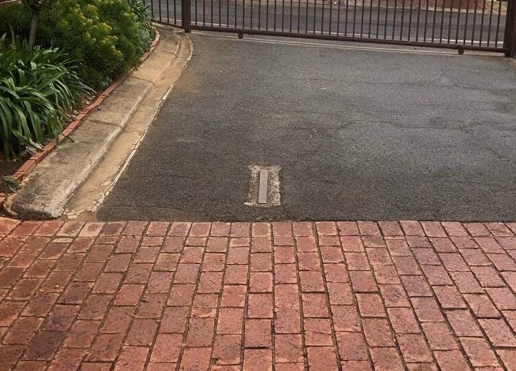 Entrance gate of Vuyo's Sanctuary in Sandton, Gauteng, ZA, surrounded by lush greenery and red brick path.