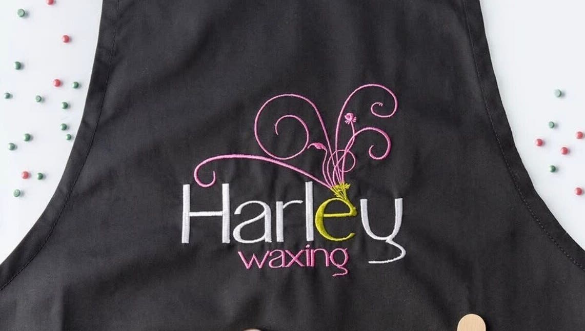 Studio M black apron with 'Harley waxing' embroidery, Lisnaskea, Northern Ireland, GB.