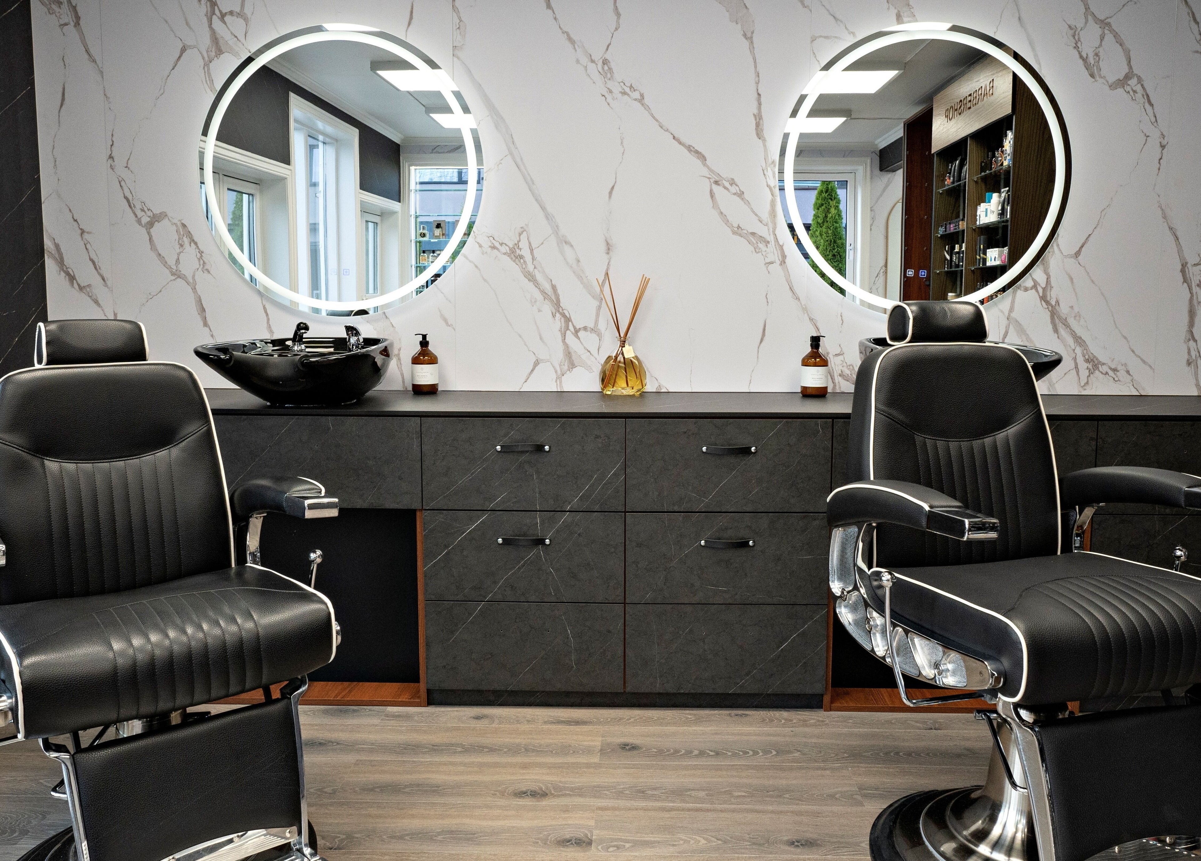 Luksuriøse frisørstoler i Alpha Grooming, Oslo, Oslo, NO, med stilige speil og marmorveggdekor.