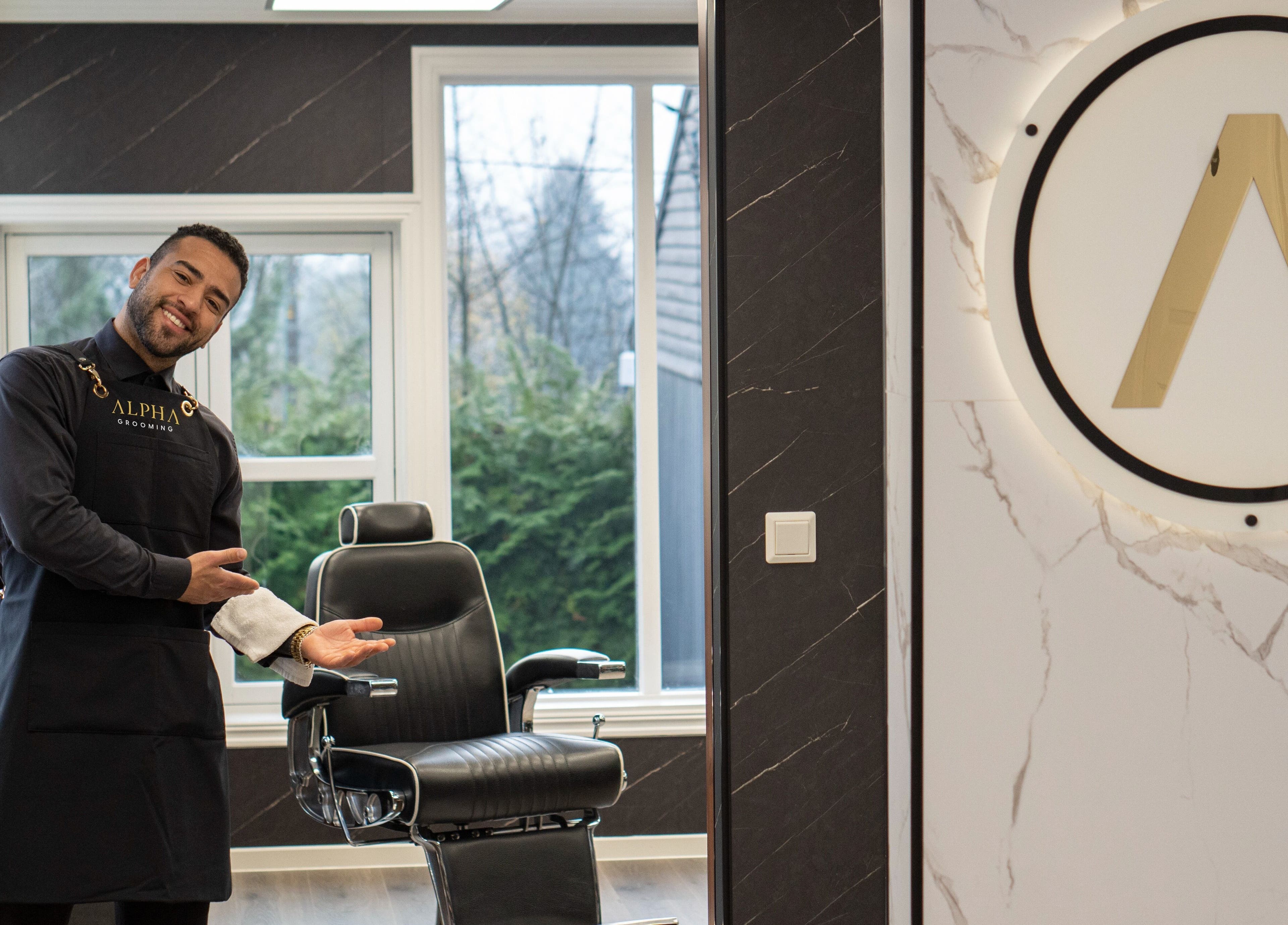 Profesjonell barberer ønsker velkommen i Alpha Grooming, Oslo, Oslo, NO, med elegant stol og moderne design.