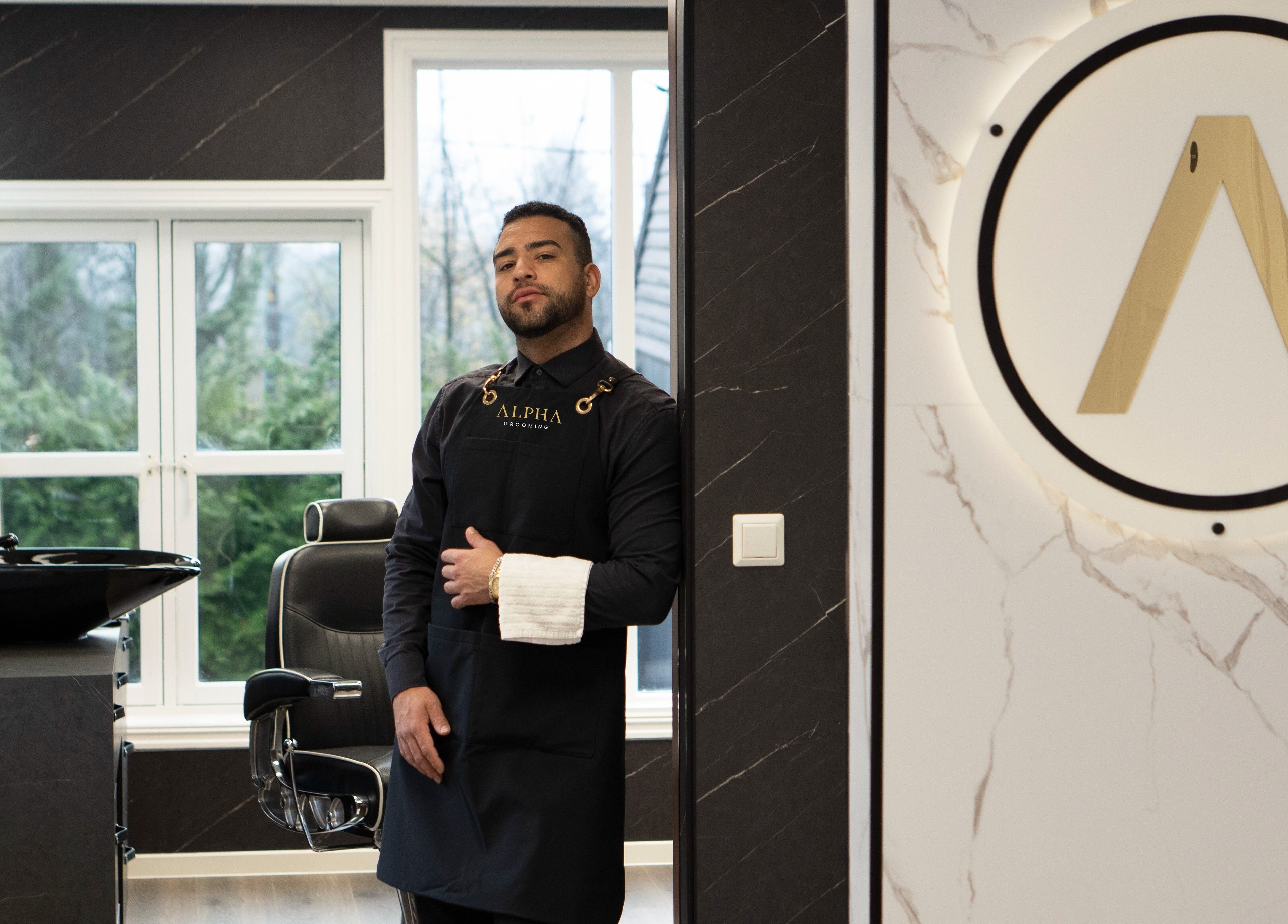 Inne i Alpha Grooming, Oslo, Oslo, NO, står en ansatt ved en frisørstol med moderne interiør.