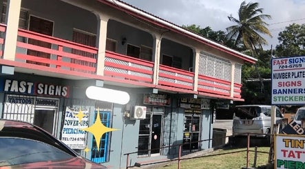 Exterior of Divine Locs & Strands at Gros Islet, Gros Islet, LC, featuring vibrant signage and lush greenery.