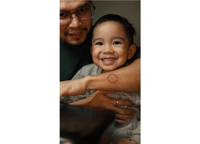 Smiling child with parent shows tattoo at ATMA TATTOO STUDIO, Mandaue, Central Visayas, PH.
