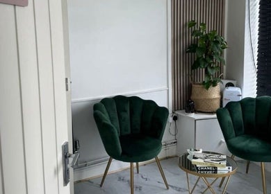 Cozy seating area at Revive Massage, Norwich, England, GB. Features plush green chairs and a stylish table.