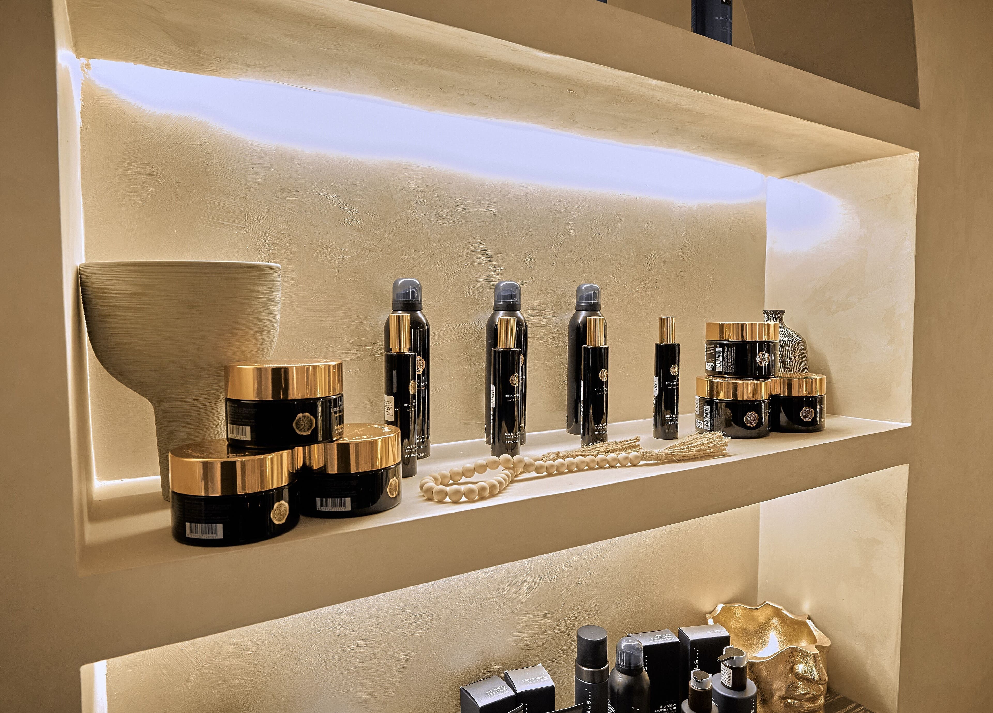 مجموعة من منتجات العناية الفاخرة مصفوفة على رف داخل Code Barber&Spa في جدة، منطقة مكة المكرمة، السعودية.