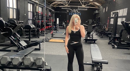 A modern gym interior at Evolve with Nicole, Denton, England, GB, featuring fitness equipment and a mirrored wall.
