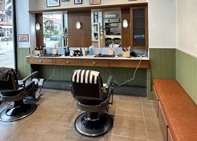 Εσωτερικό του Blade Barbershop Skg στην Ευκαρπία, GR με δύο θέσεις κομμωτηρίου και μοντέρνα διακόσμηση.