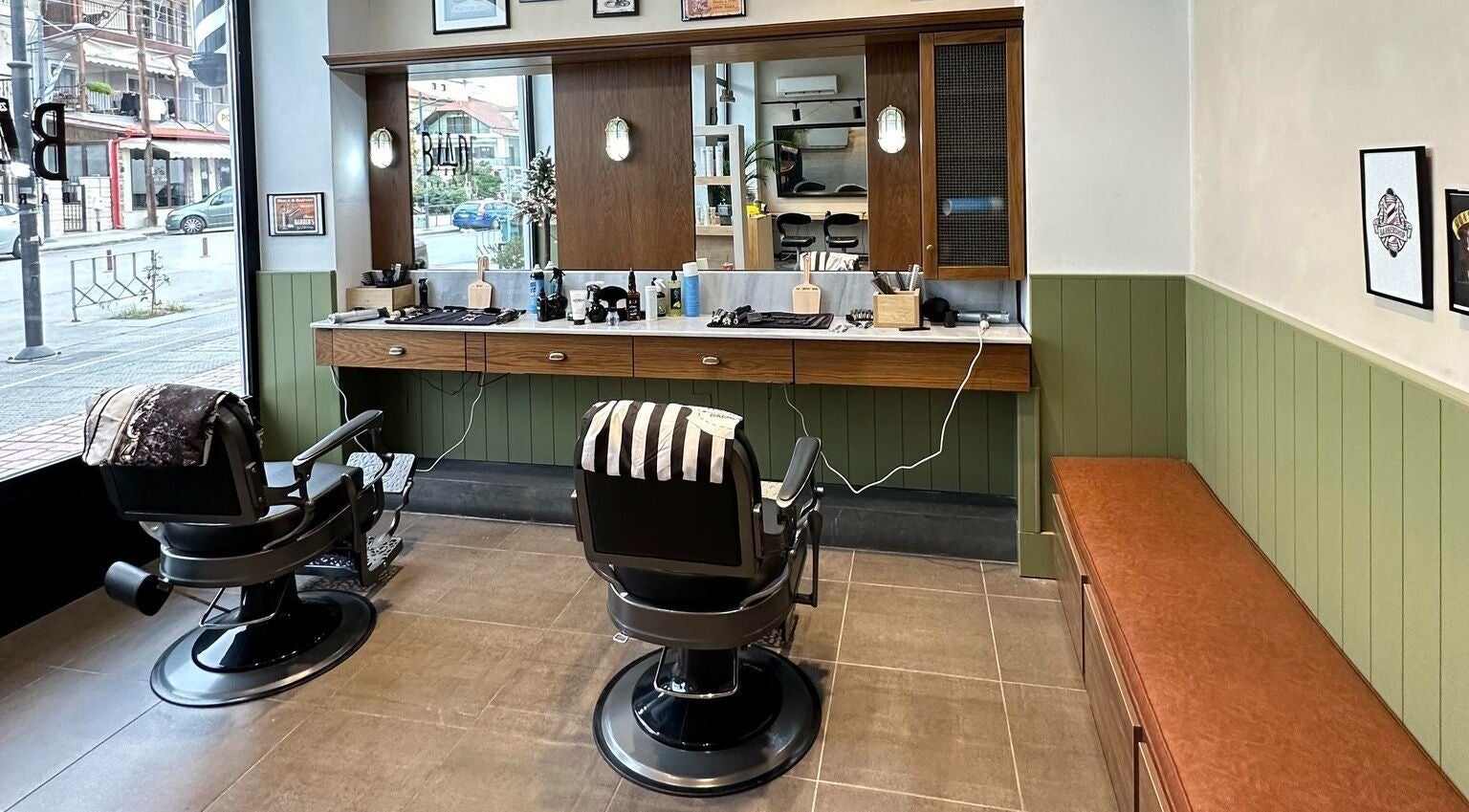 Εσωτερικό του Blade Barbershop Skg στην Ευκαρπία, GR με δύο θέσεις κομμωτηρίου και μοντέρνα διακόσμηση.