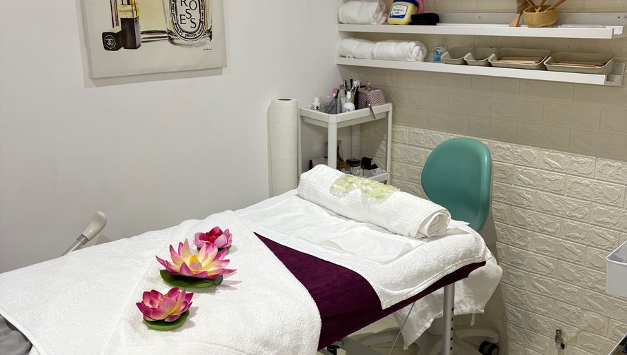 Massage room at Lulu Sparkles Braids & Beauty, Exeter, England, GB with a cozy table and lotus flowers.