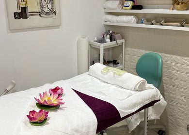 Massage room at Lulu Sparkles Braids & Beauty, Exeter, England, GB with a cozy table and lotus flowers.
