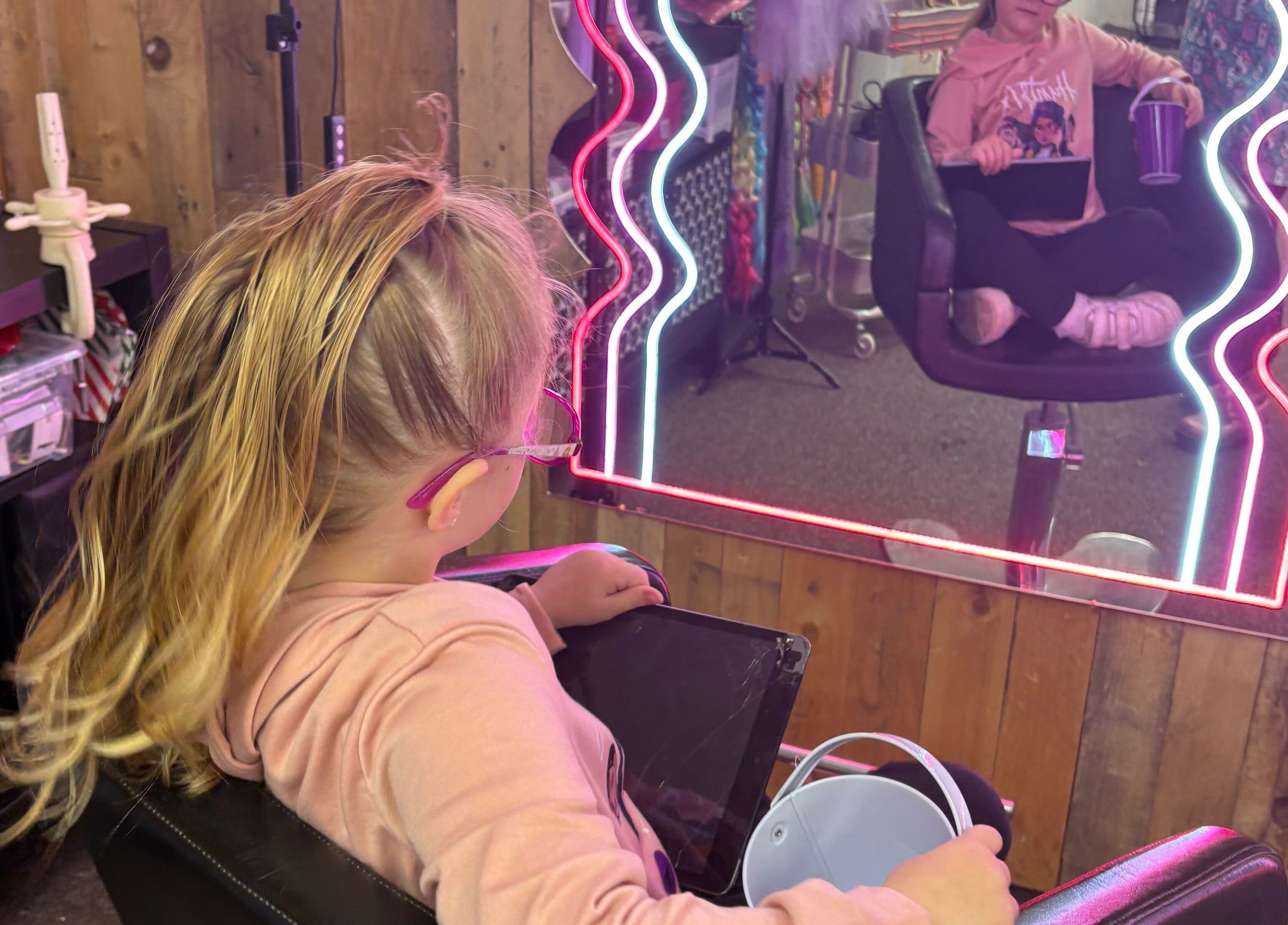 Child enjoying a makeover at Lulu Sparkles Braids & Beauty Heavitree, Exeter, England, GB, with neon mirror lights.