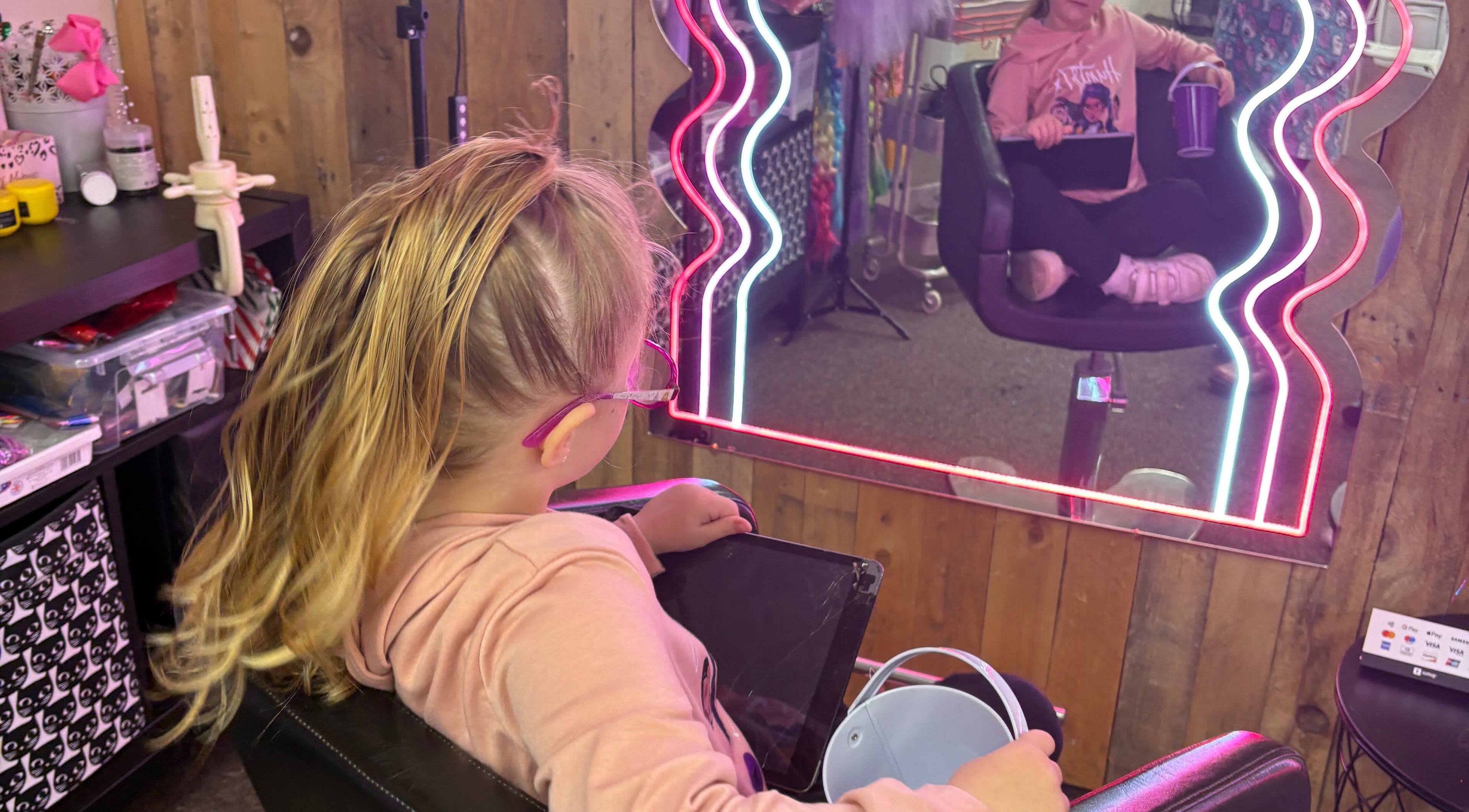 Child enjoying a makeover at Lulu Sparkles Braids & Beauty Heavitree, Exeter, England, GB, with neon mirror lights.