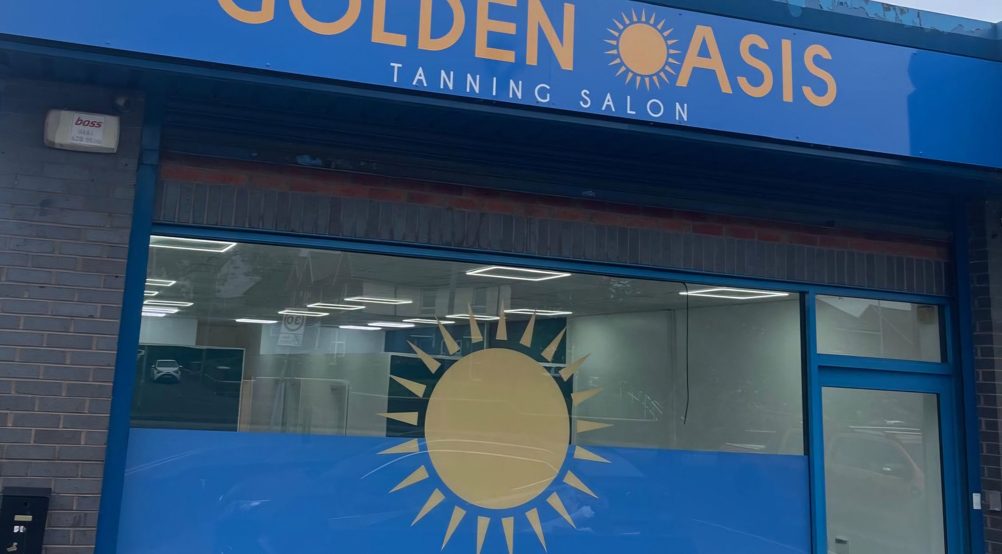 Entrance of Golden Oasis Tanning and Beauty Treatment in Rochdale, England, GB. Bright blue facade with logo.