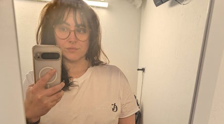 Person taking a mirror selfie at Allison Grace Sports Massage, Oldham, England, GB, wearing a branded shirt.