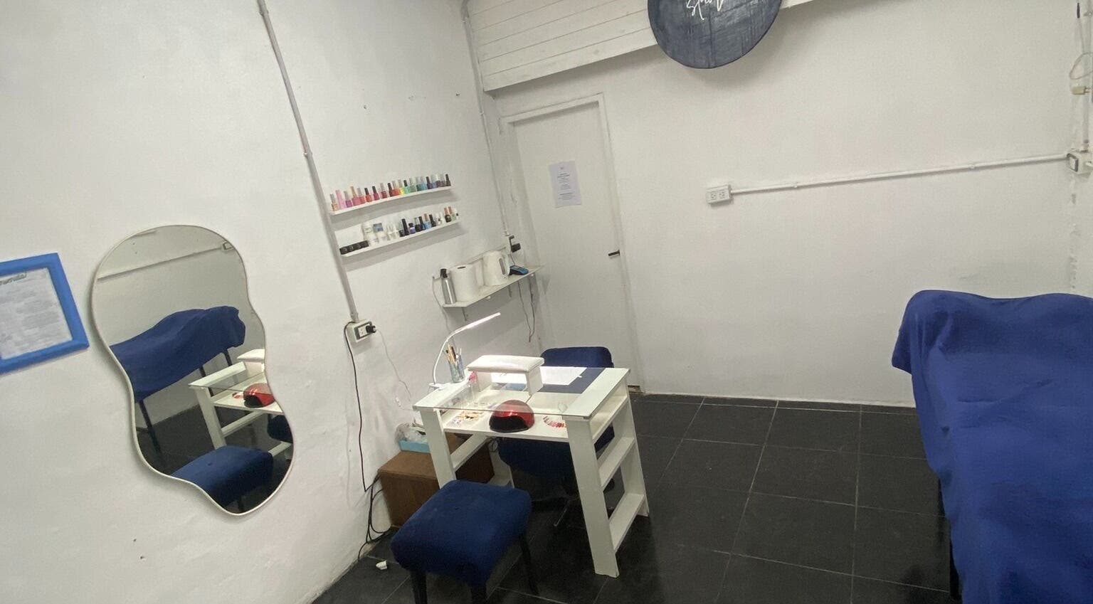 Sala de tratamiento en BYA Studio, Merlo, Provincia De Buenos Aires, AR, con mesa de manicura y espejo decorativo.