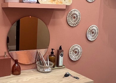 Cozy beauty station at The Vibe Cove, Tempe, Arizona, US with mirror, decor, and lotions on pink wall.
