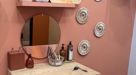 Cozy beauty station at The Vibe Cove, Tempe, Arizona, US with mirror, decor, and lotions on pink wall.