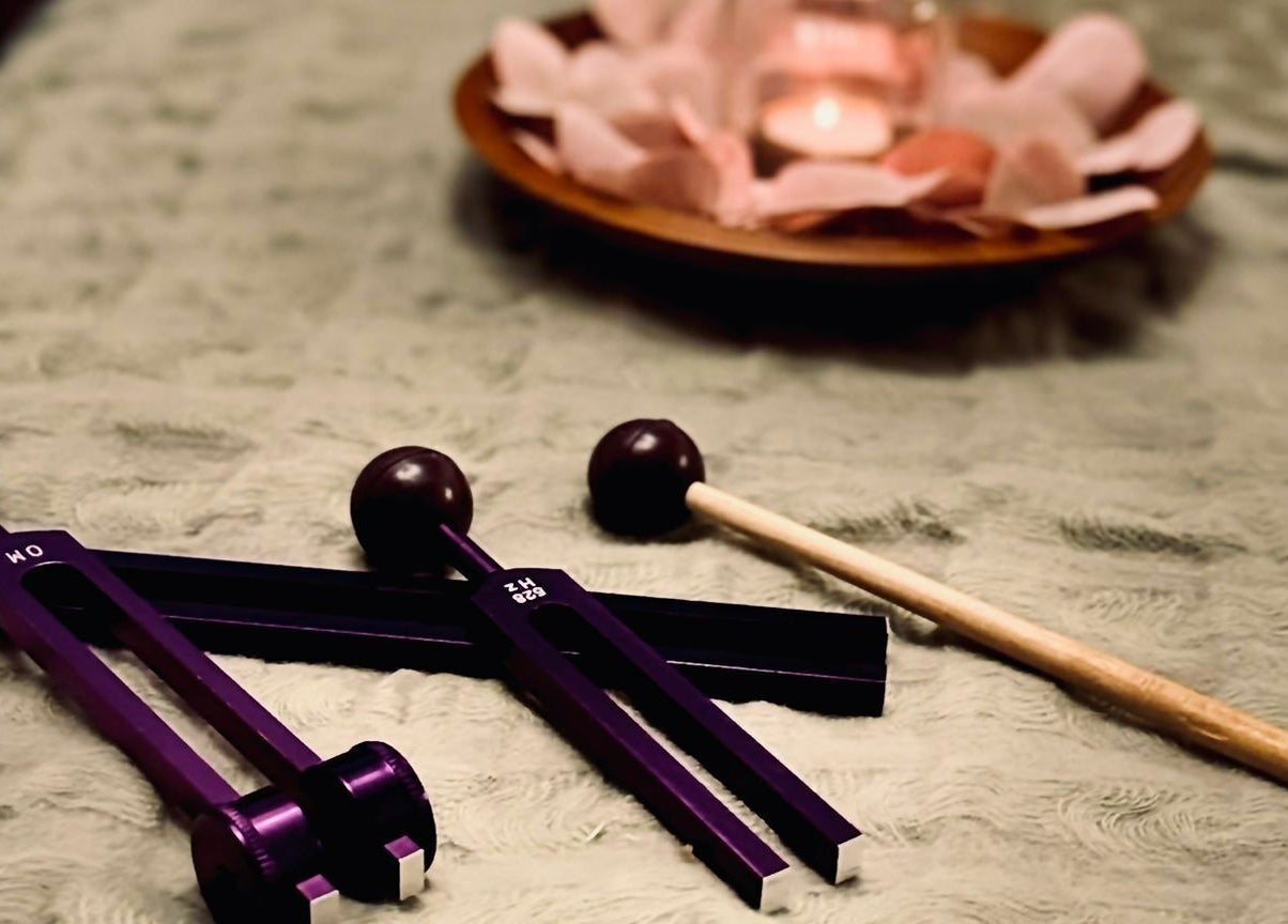 Tuning forks on a plush surface at Reforkology, Sarn, Wales, GB, set beside rose petals, symbolizing tranquility.