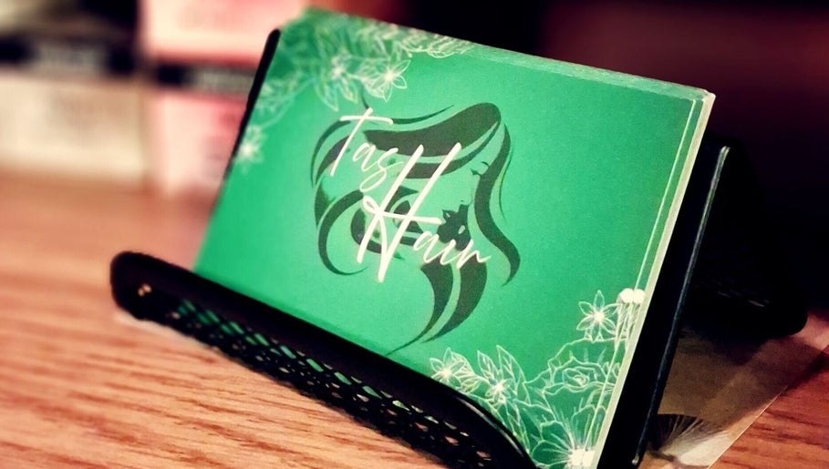 TasHair business card in a holder, Blacon, England, GB. Elegant design with floral accents.