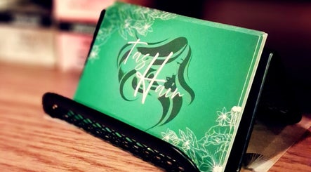 TasHair business card in a holder, Blacon, England, GB. Elegant design with floral accents.