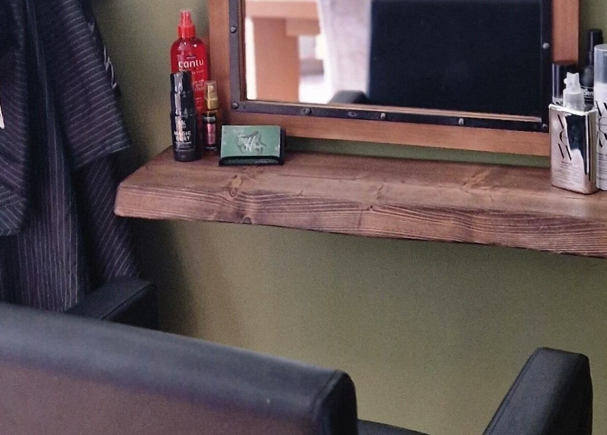 Stylish salon setup at TasHair, Blacon, England with products and a mirror on a wooden shelf.