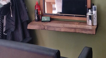 Stylish salon setup at TasHair, Blacon, England with products and a mirror on a wooden shelf.