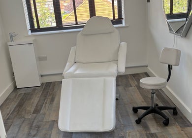 Clean, minimalist beauty treatment room at Beauty by Rhianne, Norwich, England, GB with white chair and decor.