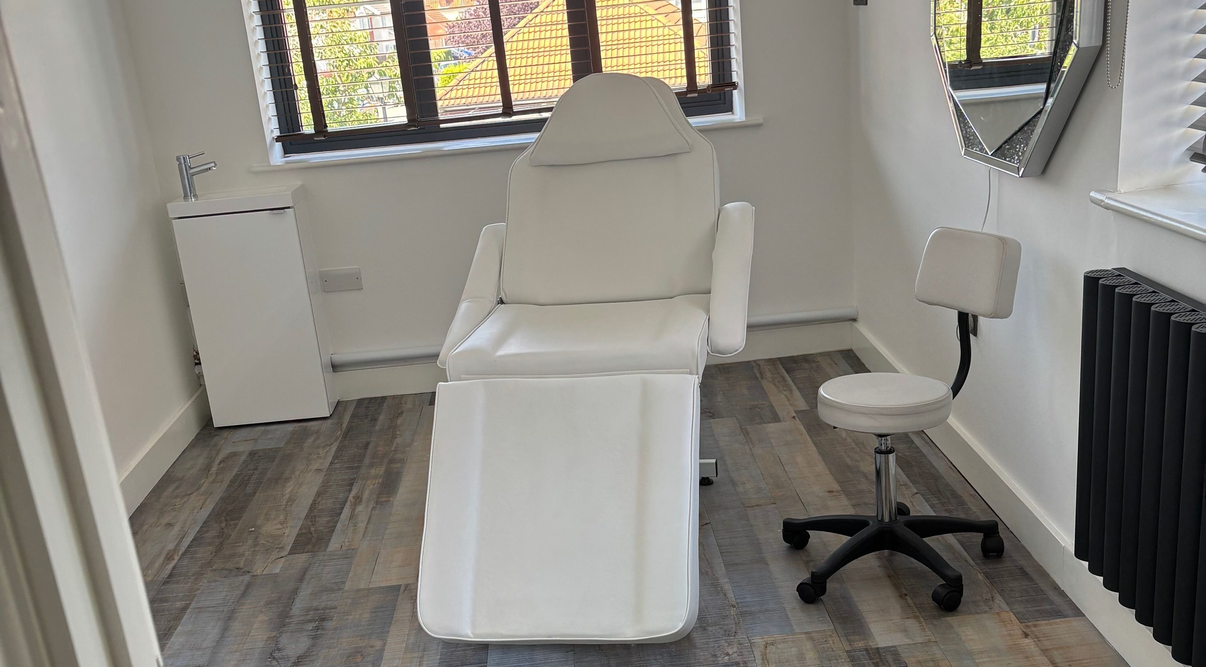 Clean, minimalist beauty treatment room at Beauty by Rhianne, Norwich, England, GB with white chair and decor.
