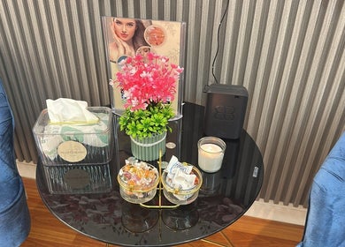 Cozy corner at Beauty Bond Salon in Riyadh with blue seating, pink flowers, and a candle on a glass table.