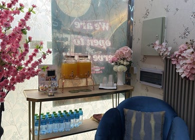 Welcoming lounge at Beauty Bond Salon in Riyadh with pink blooms and refreshments.