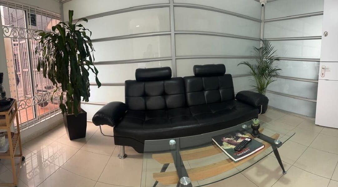 Sala de espera elegante con sofá negro en BIOSPA, Bogotá, D.c., Bogotá, D.c., CO. Ambiente acogedor y moderno.