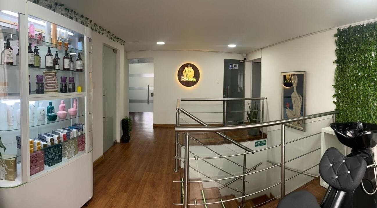 Interior de BIOSPA en Bogotá, D.C., mostrando una escalera elegante y productos de belleza.