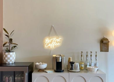 Cozy coffee corner at Minique Beauty, Richmond, Victoria, AU with neon coffee sign and elegant decor.