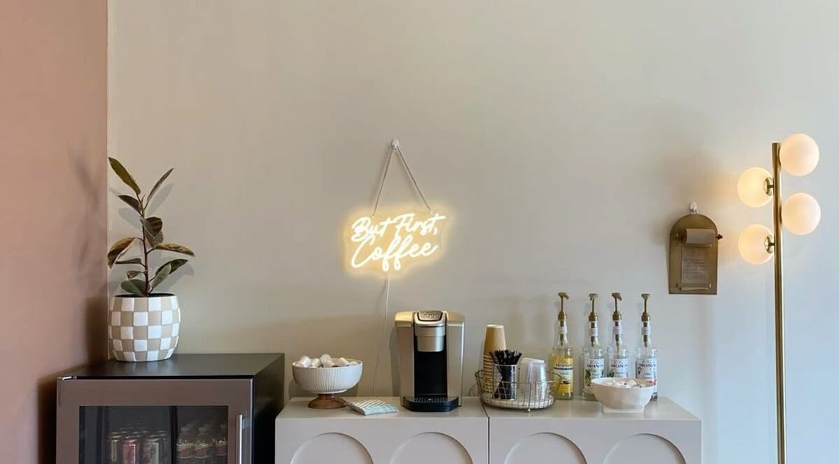 Cozy coffee corner at Minique Beauty, Richmond, Victoria, AU with neon coffee sign and elegant decor.