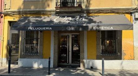 Entrada de ONDA Hair & Beauty Salon en Barcelona, Catalunya, ES con toldo negro y paredes amarillas.