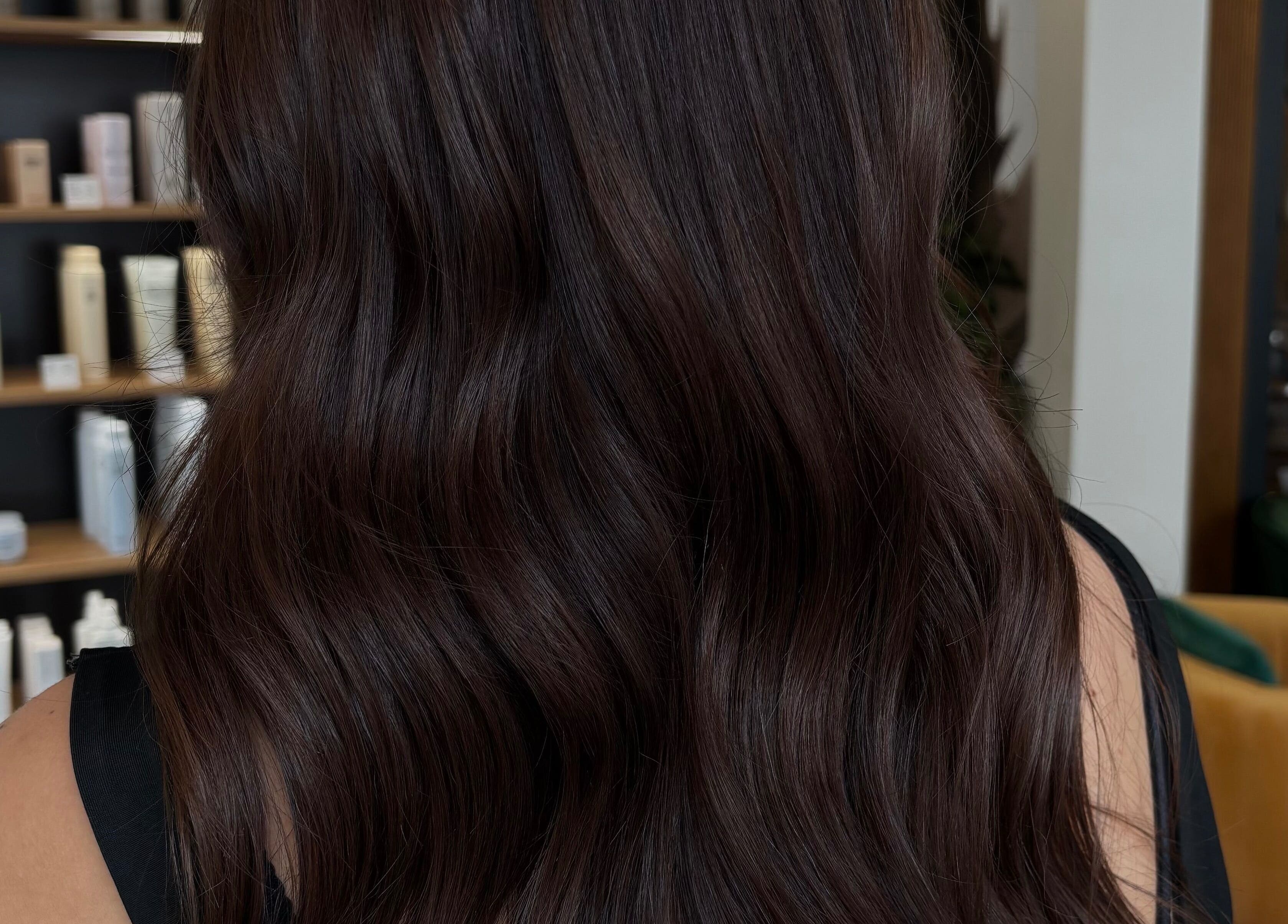 Lustrous dark hair with wavy texture at Livedinbyerinx, Aberdeen, Scotland, GB. Elegant salon environment.