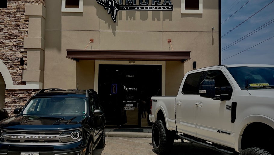 Front view of Kimura Tattoo Company, Conroe, Texas with parked cars in front.