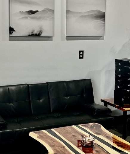 Kimura tattoo company in Conroe, Texas, US features a cozy lounge with black leather sofas and a stylish coffee table.