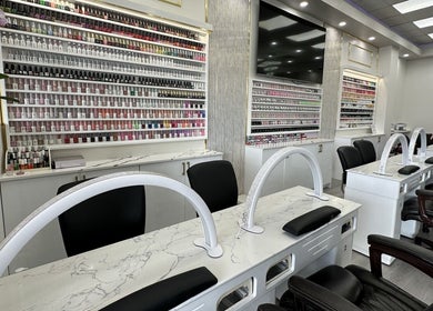 Sleek manicure stations at Maison Gloss Nail Lounge in Hamilton, Ontario, CA, showcasing a vast array of nail polishes.