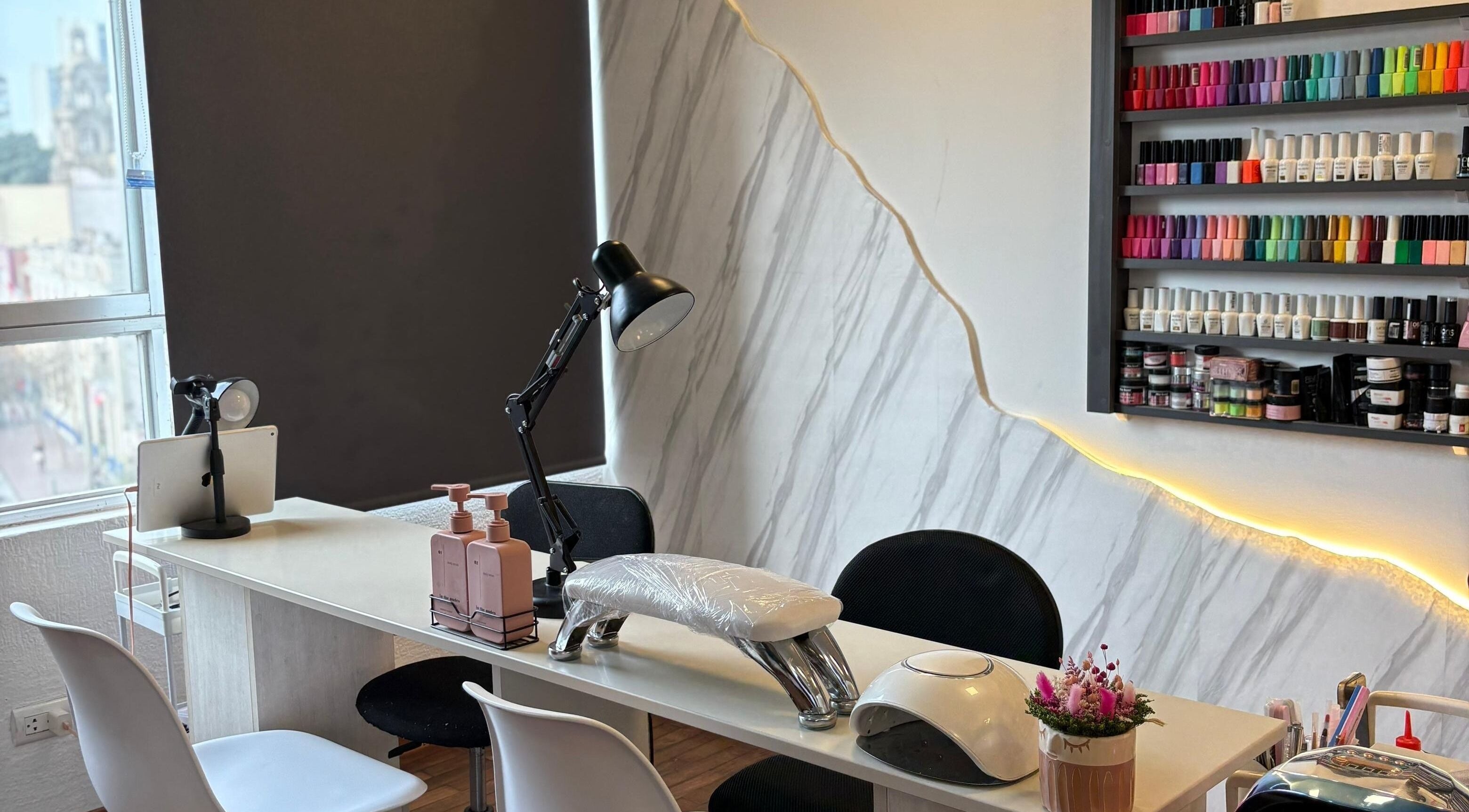 Mesa de manicura en Social Nails Club, Lima, Callao, PE, con estilo moderno y colores vibrantes de esmaltes.