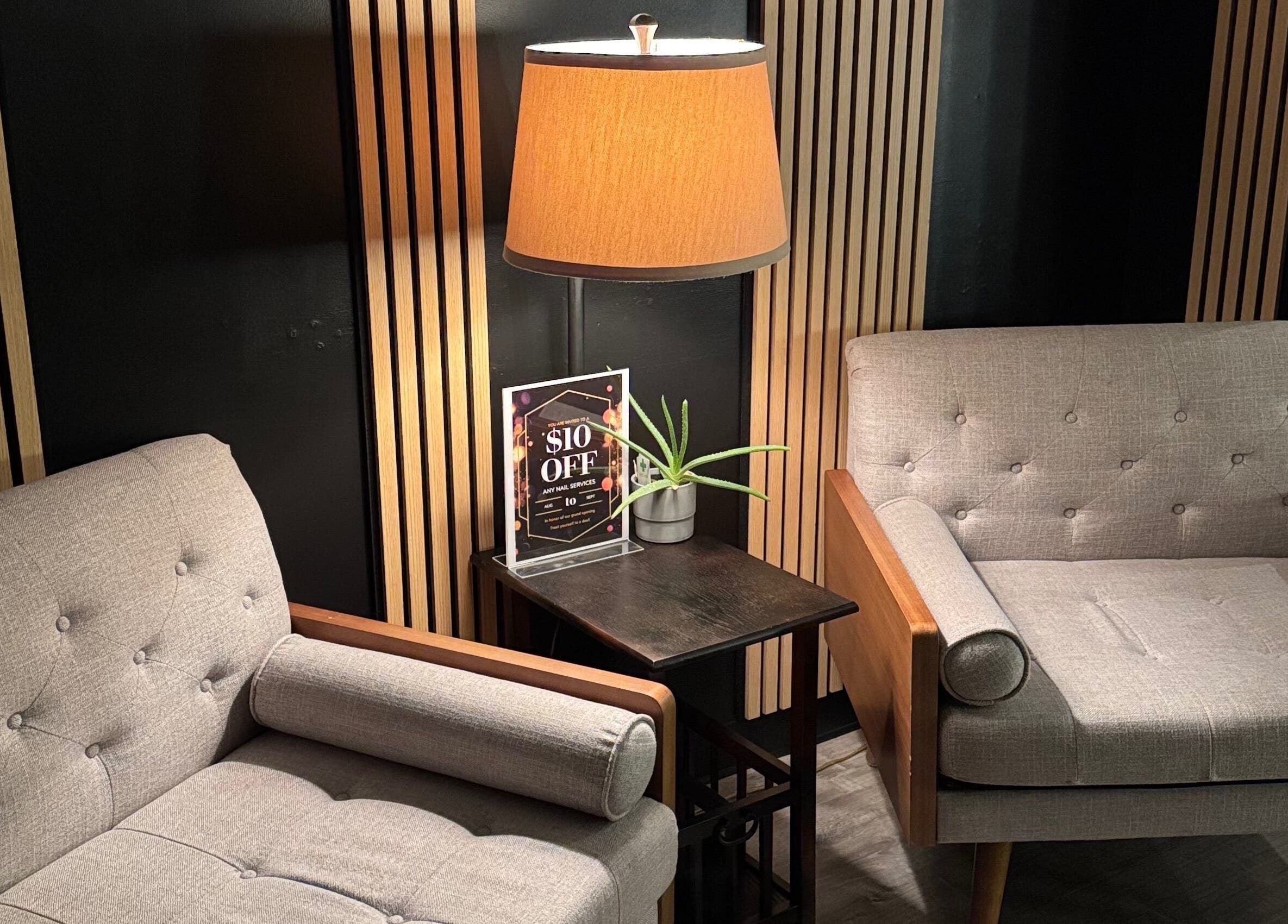Stylish waiting area at Lamour Nails, Orem, Utah, US, featuring modern chairs and a warm lamp.