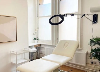 Peaceful treatment room at Aesthetic in Manchester, England, GB, featuring a plush cream chair and modern decor.